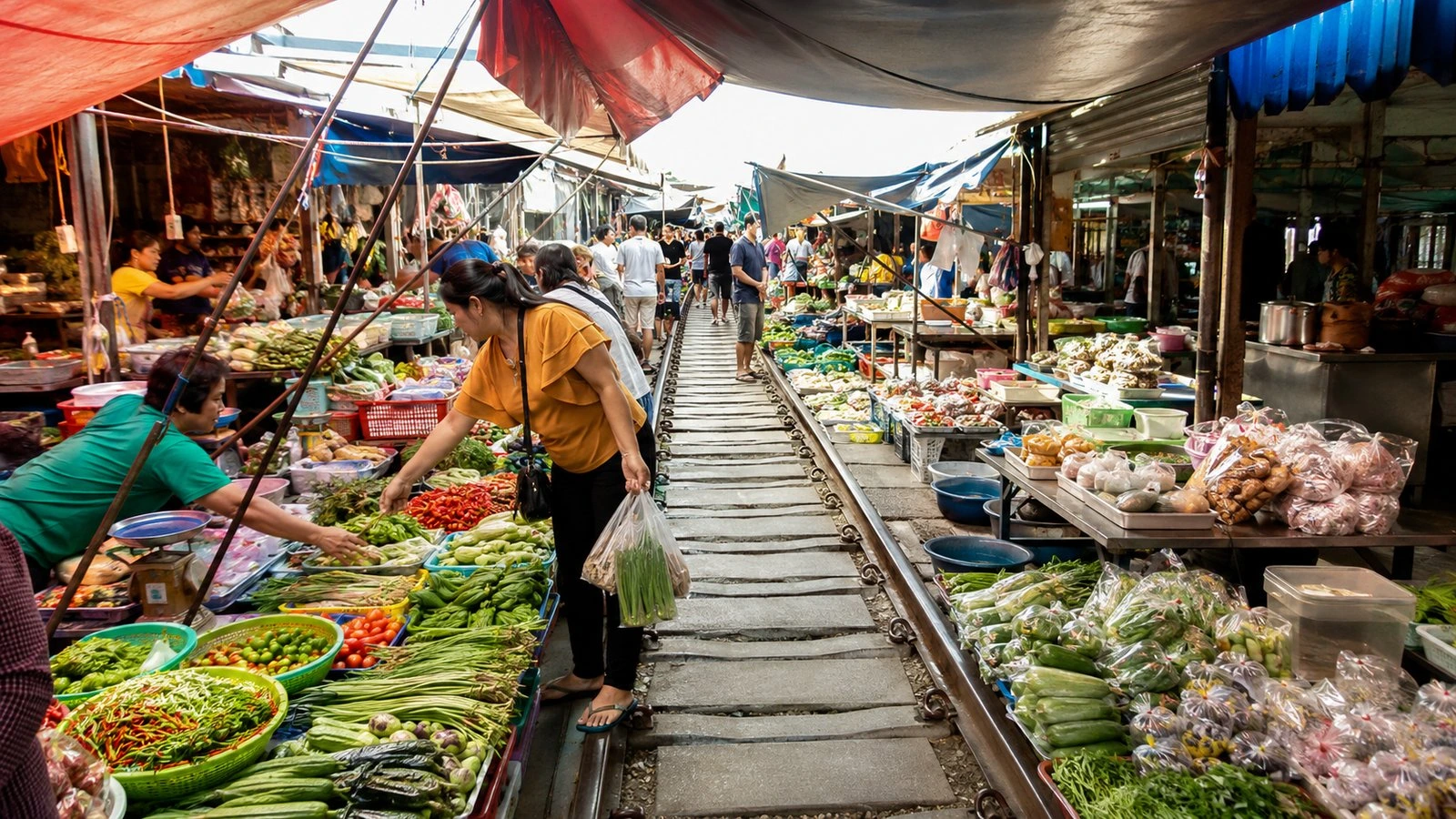 The Maeklong railway market in full swing, busy stalls with produce and seafood laid out over the tracks